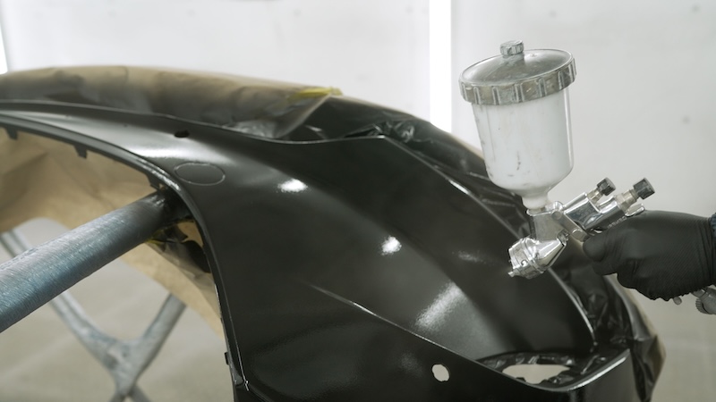 Close up of automotive paint application with high gloss finish, metallic spray gun, masked panel. Bright studio lighting highlights smooth curves reflective surface SSUCv3H4sIAAAAAAAACnSRsW7DIBCG90p9B4s5lohxnLhrpw7dukUdzoBjFAwW4FRVlHcvGJNQqd24747/7r+7Pj8VBerACopeimuIfCyknK0z4IRWHuPNyg1XjJucXAxpcA5A5BFnwmkjQOawA0cHBSP3UM1SBnxbksg6cLPlNsyyIgqOn7xGhHeJOPAxxkVKLEn/w6fQhwFlJ21ctLHJKuzchYpXMBYlHNv9o/WmWFhIMPKHzjuouQcanKrTQzA+Pu+bOXFFvxdnmWPDJYfo+BhL0fnLcTPmO4CZCZ3Zv2gKMhSQTAnEBAZ+/ZuMoGGkB9FuWA6YlKielTNhKpScIan1BJ0M5+l9G574ANb6cpZ41pv67egx66O0Wzytqoj5K4ZwS2pCKtyQiuz2h32F27UgXn4QXmcZJwn5mJ4Fy12JMAHa8qbe4hqXuKVtWUPHypZXu3Lf103f8qbfHai/xe0HAAD//wMA22/oAuICAAA=